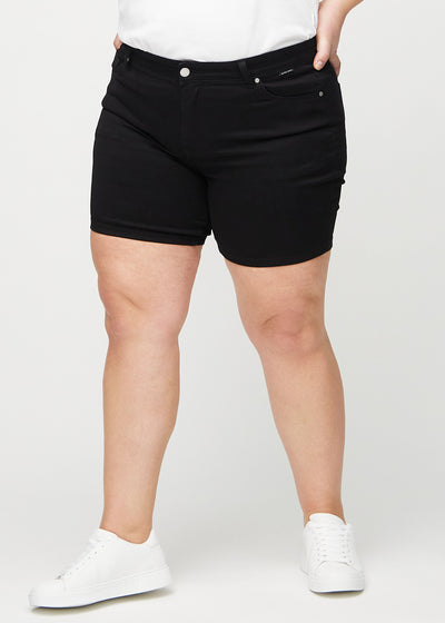 Sorte skinny short shorts, modelnavn Ravens, som sidder tæt til, og slutter midt på låret på en plus-size model, set forfra.