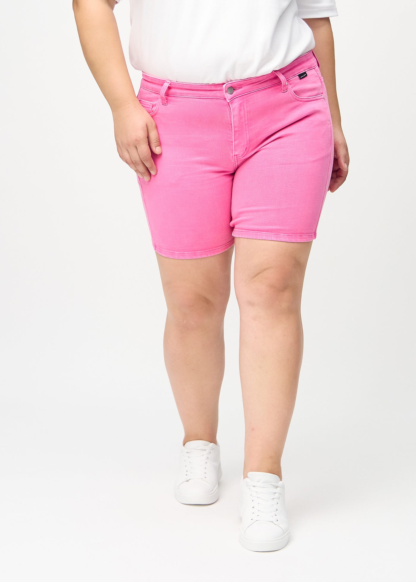 Lyserøde skinny short shorts, modelnavn Flamingos, som sidder tæt til, og slutter midt på låret på en plus-size model, set forfra.