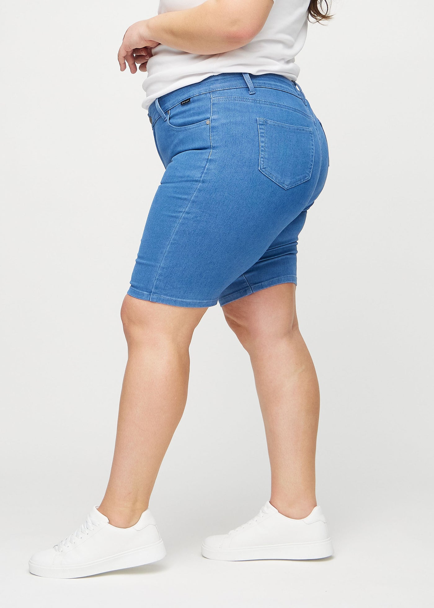 Blå skinny middle shorts set fra siden på en plus-size model.