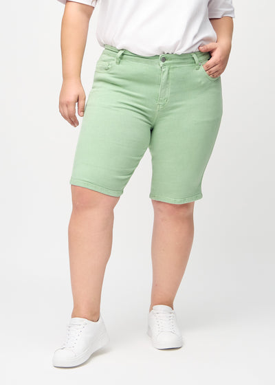 Lysegrønne skinny middle shorts, modelnavn Mints, som sidder tæt til låret og slutter lige over knæet på en plus-size model, set forfra.