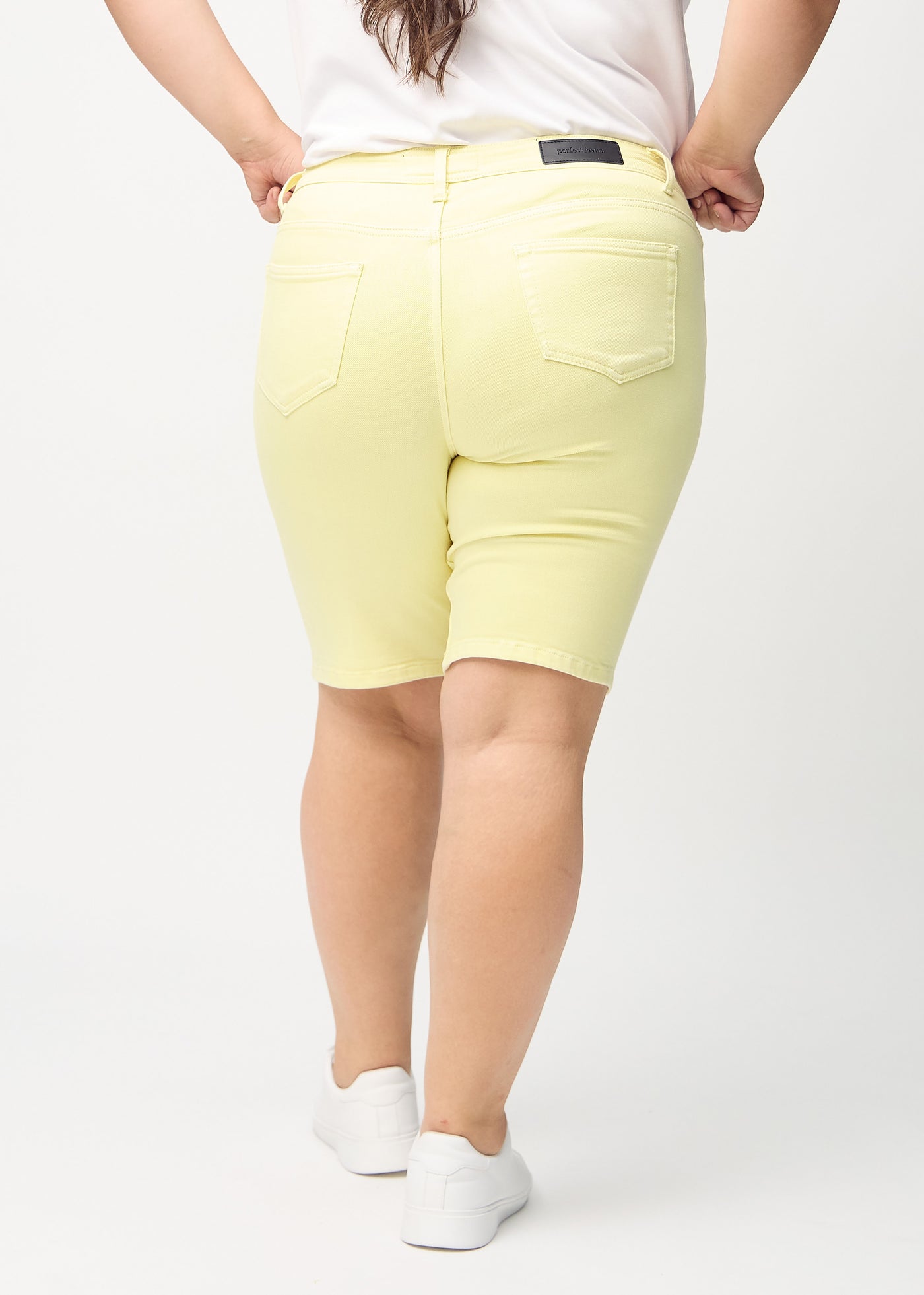 Lysegule skinny middle shorts set bagfra på en plus-size model, så man kan se hele produktet.