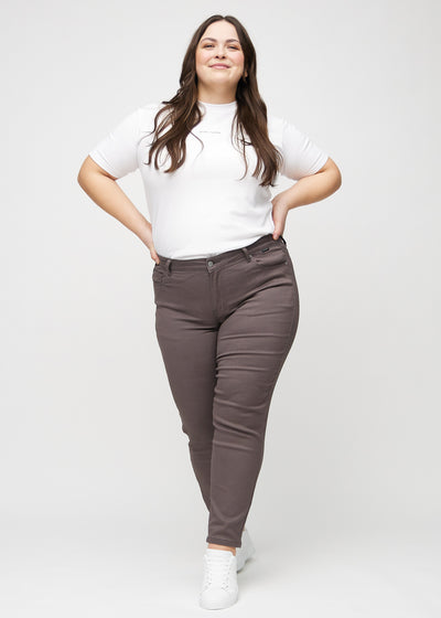 Fuldt billede af en plus-size model i gråbrune slim jeans.