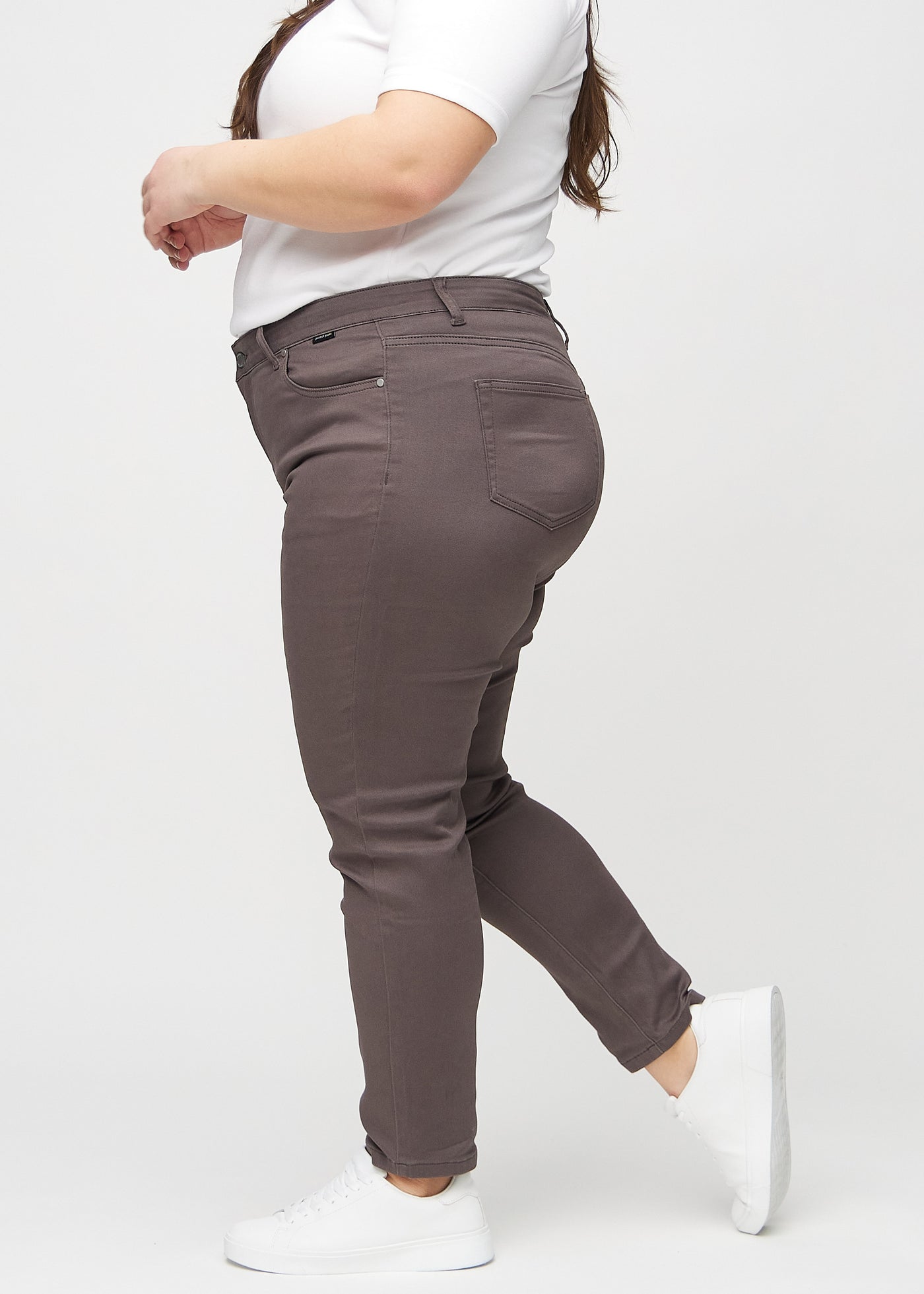 Gråbrune slim jeans set fra siden på en plus-size model.