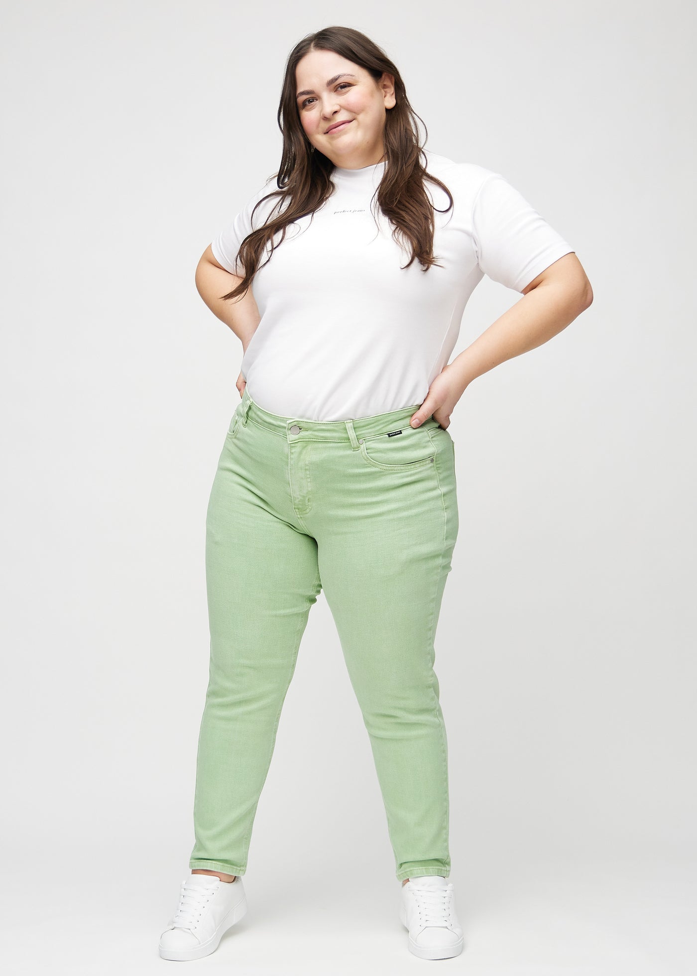 Fuldt billede af en plus-size model i lysegrønne slim jeans.